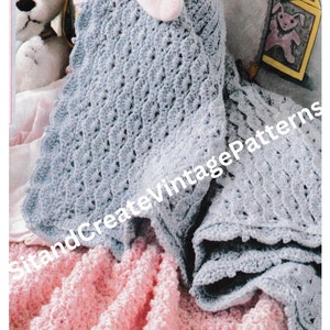May include: Two crocheted baby blankets, one in pink and one in blue, with a white bunny and a teddy bear in the background.  The blankets are made with a delicate stitch pattern and have a scalloped edge.