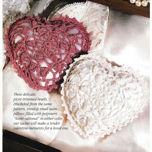 May include: Two crocheted heart-shaped sachets, one pink and one white, with picot edging. The sachets are filled with potpourri and are a perfect Valentine's Day gift.