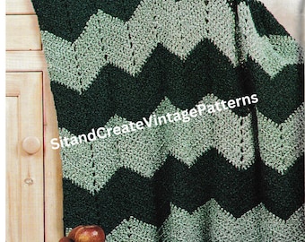 May include: A green and white crocheted ripple afghan with a chevron pattern and fringe. The afghan is draped over a wooden cabinet with a vase of sunflowers and a ceramic pitcher on top.
