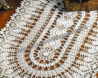 Può includere: Un runner da tavolo ovale in crochet bianco con un delicato motivo floreale. Il runner è realizzato con un filo sottile e ha un aspetto traforato.