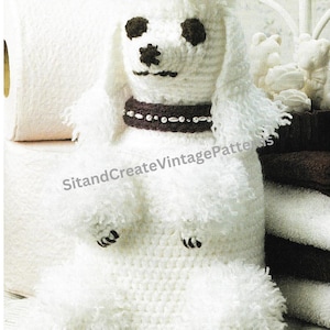 May include: White crocheted poodle tissue box cover with black eyes and a brown collar with white beads. The poodle is sitting on a white wicker chair.
