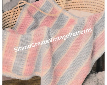 May include: A pink and blue striped crocheted baby blanket in a wicker basket. The blanket is made with a simple stitch pattern and has a delicate, feminine feel.