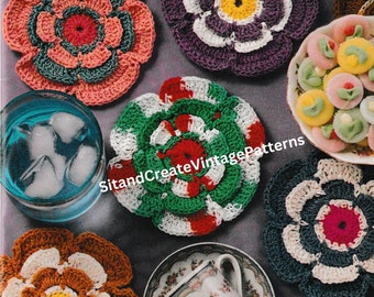 May include: Six crocheted flower coasters in various colors, including green, red, white, purple, pink, and brown. The coasters are arranged on a gray surface with a glass of ice water, a cup and saucer, and a plate of candy.