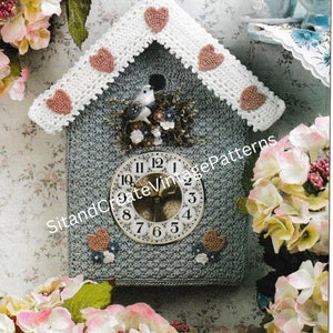 Peut inclure: Une horloge en forme de nichoir à oiseaux en crochet avec une bordure en dentelle blanche et des cœurs roses. Le cadran de l'horloge a des chiffres romains et une figurine d'oiseau est perchée sur le toit.