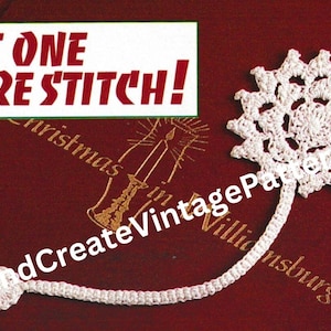 May include: White crocheted snowflake bookmark with a long chain attached. The bookmark is on a red book with the text "Just One More Stitch!" and "Sit and Create Vintage Patterns".