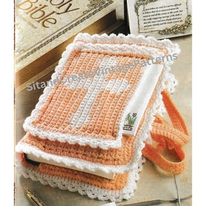 May include: A crocheted book cover in peach and white with a white crocheted edging. The cover is sitting on top of a closed book with the words "Holy Bible" on the cover.