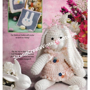 Puede incluir: Un patrón de crochet para un conejito de peluche con un vestido rosa y pelaje blanco. El patrón incluye instrucciones para hacer un conejito de peluche y dos agarraderas para ollas. Las agarraderas para ollas están crocheteadas en un diseño de cesta y conejito. El texto en la página dice "Nuestras agarraderas para ollas de Pascua se tejerán tan rápido como un conejito! ¡Hip, hip, hop por el sendero! Este conejito de Pascua está vestido para la ocasión con botones y lazos. El patrón comienza en la página 28."