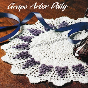 May include: White crochet doily with a grape arbor design. The doily has a scalloped edge and is decorated with purple grapes.