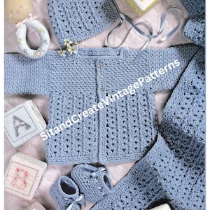 May include: A crochet baby set in a light blue colour, including a hat, cardigan, booties, and a blanket. The set is laid out on a white and pink patterned surface.