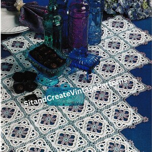 May include: A vintage-style table setting featuring a white and blue crocheted doily. Decorative glass bottles in shades of blue, green, and purple are arranged on the table. The image also includes a dish of chocolates and the text "SitandCreateVintagePatterns."