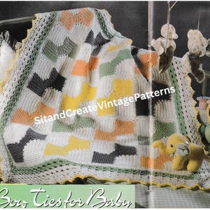 May include: A handmade crochet baby blanket with a bow tie pattern in white, yellow, orange, green, and gray. The blanket has a scalloped edge and the text "Bow Ties for Baby". The blanket is displayed in a crib.