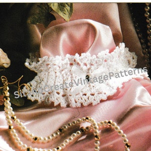 May include: White crocheted lace collar with a white button in the center. The collar is displayed on a pink satin fabric with a pearl necklace.