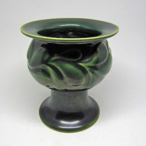 Peut inclure: Un vase en céramique vert avec un motif de feuilles. Le vase a une large ouverture et une base ronde.