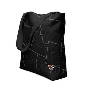 May include: Black tote bag featuring a topographic map design in shades of gray. The bag has a rectangular shape with a shoulder strap and a small logo in the bottom right corner. The bag is made of a durable material.