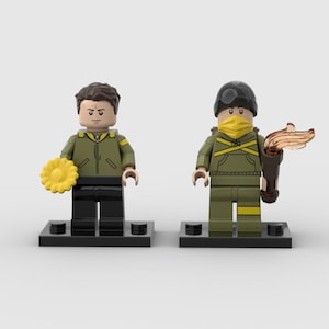 May include: Two Lego figures, one holding a yellow flower and the other a torch. Both figures wear olive green jackets, black pants, and are on black bases. One figure has a black helmet and yellow face covering.