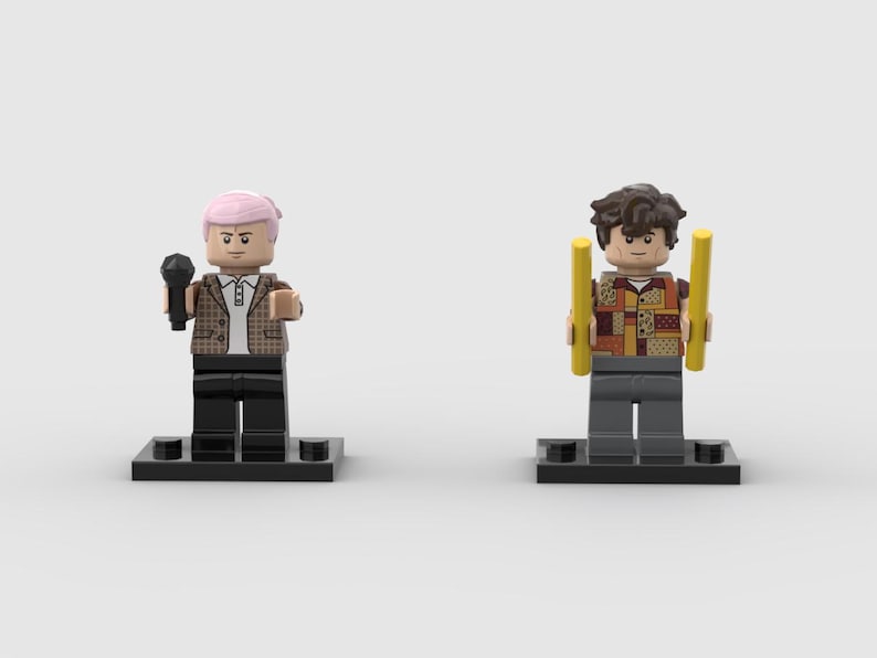 May include: Two Lego figures on black bases. One figure has pink hair, a brown plaid jacket, and holds a black microphone. The other figure has brown hair, a patchwork shirt, and holds two yellow batons.