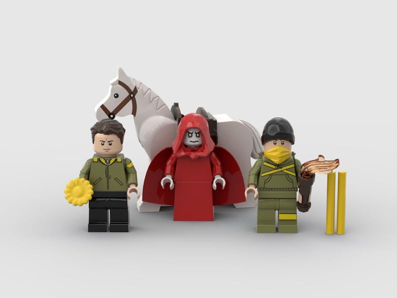 May include: A Lego scene featuring three minifigures and a white horse. One minifigure wears a red hooded robe, another a green jacket and black pants, and the third a green uniform with a yellow mask. Accessories include a torch and a yellow flower.