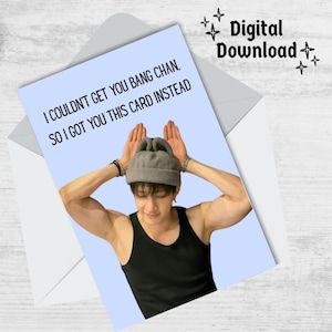 May include: A light blue card with the text "I couldn't get you Bang Chan, so I got you this card instead."  A photo of a man with dark hair wearing a grey beanie and a black tank top is on the card. The man is making bunny ears with his hands.