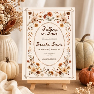 May include: A rectangular invitation card featuring a brown floral border and an oval frame. The text reads: Falling in Love, JOIN US FOR A BRIDAL SHOWER IN HONOR OF Brooke Davis, 19 JUNE 2030, AT 10.00 PM, 123 Anywhere St., Any City, Let's gather together.