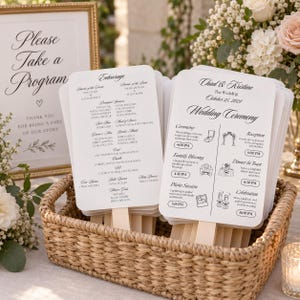 May include: A stack of white wedding program fans with wooden handles in a woven basket. The programs feature black text detailing the wedding ceremony schedule for Chad and Kristine on October 25, 2024, and a list of the wedding entourage members.