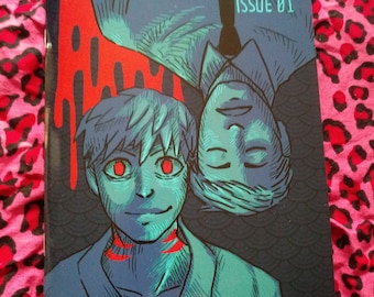 May include: A comic book cover with the title "COMPILER" and the issue number "ISSUE 01". The cover features two men with blue and green skin tones, one lying upside down with red dripping down the page. The background is a dark blue with a pattern of scales.