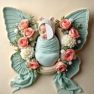 Op de afbeelding: Een pasgeboren baby gewikkeld in een lichtblauwe deken ligt in een wit vlindervormig nest. Het nest is versierd met roze en witte bloemen. De baby draagt een witte gebreide muts.