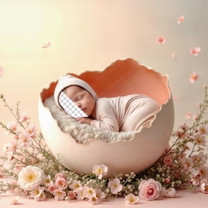 May include: A baby in a white hat and pink onesie lies inside a large, cracked eggshell. The eggshell is surrounded by pink flowers and greenery, with more flowers and petals scattered around, creating a soft, pastel scene.