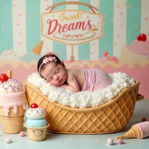 May include: A newborn baby girl sleeping in a waffle cone-shaped bed decorated with white fluffy clouds. The bed is surrounded by various ice cream-themed props, including a large pink ice cream cone with sprinkles and a smaller blue ice cream cone with a smiling face. The background features a pastel striped pattern with the words "Sweet Dreams" on a sign.