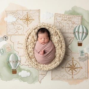 Puede incluir: Un bebé recién nacido envuelto en una manta rosa, acurrucado en una cesta tejida beige. El fondo presenta elementos temáticos de viaje: mapas, brújulas, globos aerostáticos, nubes y sellos postales. El tema general es el viaje y la aventura.