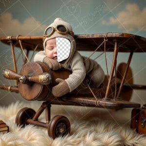 May include: A baby wearing a brown aviator hat and goggles is sleeping in a wooden toy airplane. The airplane has a brown leather suitcase next to it.