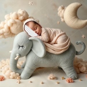 May include: A sleeping baby wearing a pink outfit is lying on a plush gray elephant toy. The elephant is surrounded by white fluffy clouds and a crescent moon. The background is a light blue and white textured surface.
