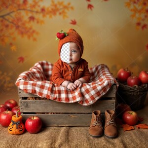 May include: A baby in an orange outfit and hat with an apple accent sits in a wooden crate lined with a red and white checkered blanket. Red apples and brown boots are arranged around the crate, with a pumpkin decoration. The background features autumn leaves.