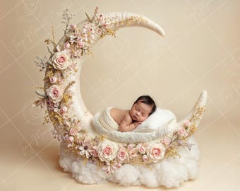 May include: A newborn baby sleeping in a white crescent moon shaped prop decorated with pink and white flowers. The prop is sitting on a white fluffy cloud.