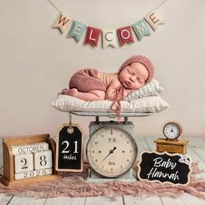 May include: A newborn baby wearing a pink hat and outfit, sleeping on a pillow atop a vintage scale. The scale reads 7.5 lbs. A banner says "WELCOME". A chalkboard sign says "Baby Hannah". A wooden calendar shows October 28, 2025. A tag says "21 inches".