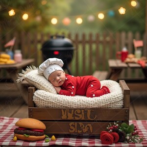 May include: A sleeping baby wearing a chef's hat and red outfit, resting on a small bed with a white blanket. The bed is inside a wooden crate with the words "Visit Siba" on it. A large hamburger sits on a red and white checkered tablecloth.