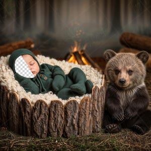 Puede incluir: Un bebé recién nacido con un atuendo y gorro verde oscuro descansa en una cuna de madera forrada con piel blanca. Un osezno pardo está sentado cerca. El fondo presenta una fogata y troncos, creando un tema de bosque.