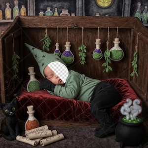 May include: A baby dressed as a wizard sleeps in a wooden box, surrounded by potion bottles and a black cat figurine. The scene is lit by lanterns and evokes a magical, whimsical theme. The baby wears a green hat with stars.