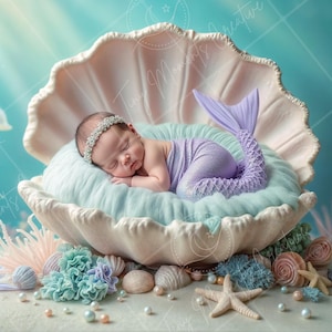 May include: A newborn baby dressed as a mermaid sleeps in a large white seashell. The baby is wearing a purple tail and a crown. The seashell is surrounded by seashells, pearls, and starfish.