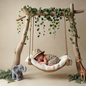 Può includere: Un neonato con un cappello marrone e vestiti color kaki dorme in un'amaca bianca appesa a una struttura in legno decorata con viti verdi. Un elefante grigio e una giraffa marrone di peluche sono sul pavimento.