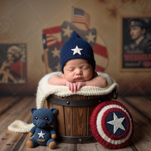 Può includere: Un bambino che dorme con un cappello blu navy con una stella bianca, adagiato in una botte di legno. Un orsacchiotto blu con una stella bianca e uno scudo rosso, bianco e blu sono nelle vicinanze. Lo sfondo presenta bandiere americane e poster vintage.
