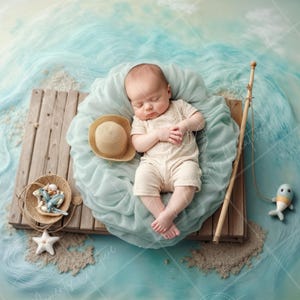 May include: A newborn baby wearing a white onesie is sleeping on a wooden dock with a blue and green background. The baby is surrounded by a light blue fabric and a straw hat. There is a fishing rod and a blue fish toy on the dock.