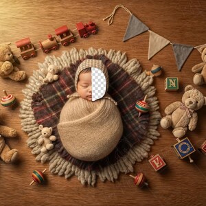 May include: A newborn baby wrapped in a beige blanket and hat, surrounded by teddy bears, wooden toys, and a decorative banner. Toys include a train set, spinning tops, and alphabet blocks. The scene is set on a wooden surface.