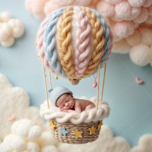 Könnte beinhalten: Ein neugeborenes Baby schläft in einem Korb, der wie ein Heißluftballon geformt ist. Der Ballon ist aus Garn gefertigt und hat ein rosa, blaues und gelbes Farbschema. Der Korb ist mit weichem, flauschigem Material ausgekleidet. Der Hintergrund ist hellblau mit weißen, flauschigen Wolken.