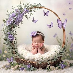 Peut inclure: Un nouveau-né dort dans un panier en osier décoré de fleurs violettes et de papillons. Le panier est entouré d'une couronne de fleurs violettes et de feuilles vertes.