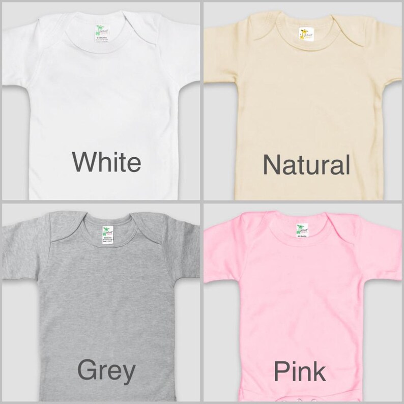 four different colored baby shirts, each with a label indicating the color: white, natural, grey, and pink.