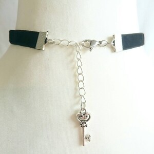 May include: A black velvet choker necklace with a silver chain and a key charm. The chain is adjustable and the key charm is a decorative detail.