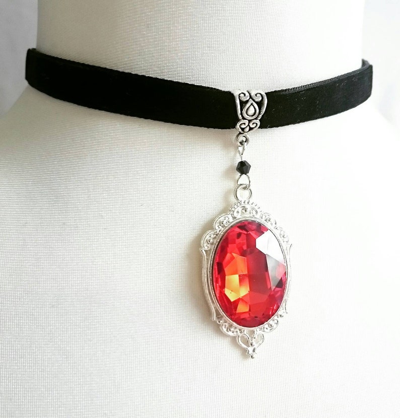 May include: A black velvet choker with a silver pendant featuring a large red gemstone in an ornate setting.