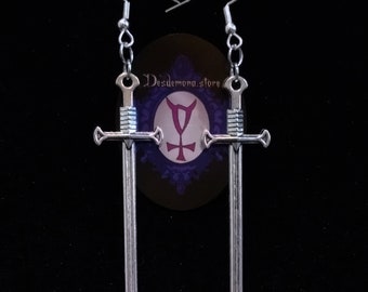 May include: A pair of silver sword earrings. The swords are crossed and have a detailed design. The earrings are hanging from silver hooks.
