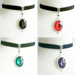 May include: Four black velvet choker necklaces with silver pendant charms featuring large oval-shaped gemstones. The gemstones are black, red, green, and purple.