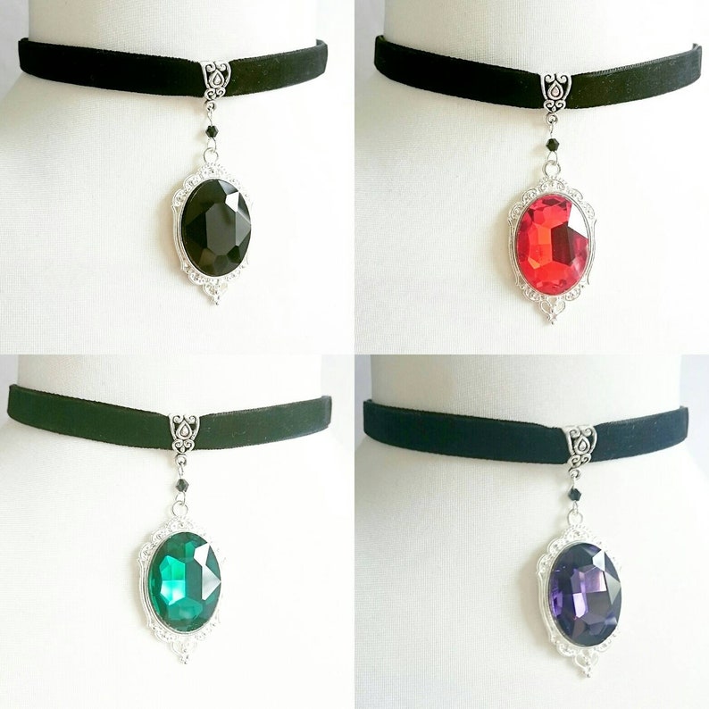 May include: Four black velvet choker necklaces with silver pendant charms featuring large oval-shaped gemstones. The gemstones are black, red, green, and purple.
